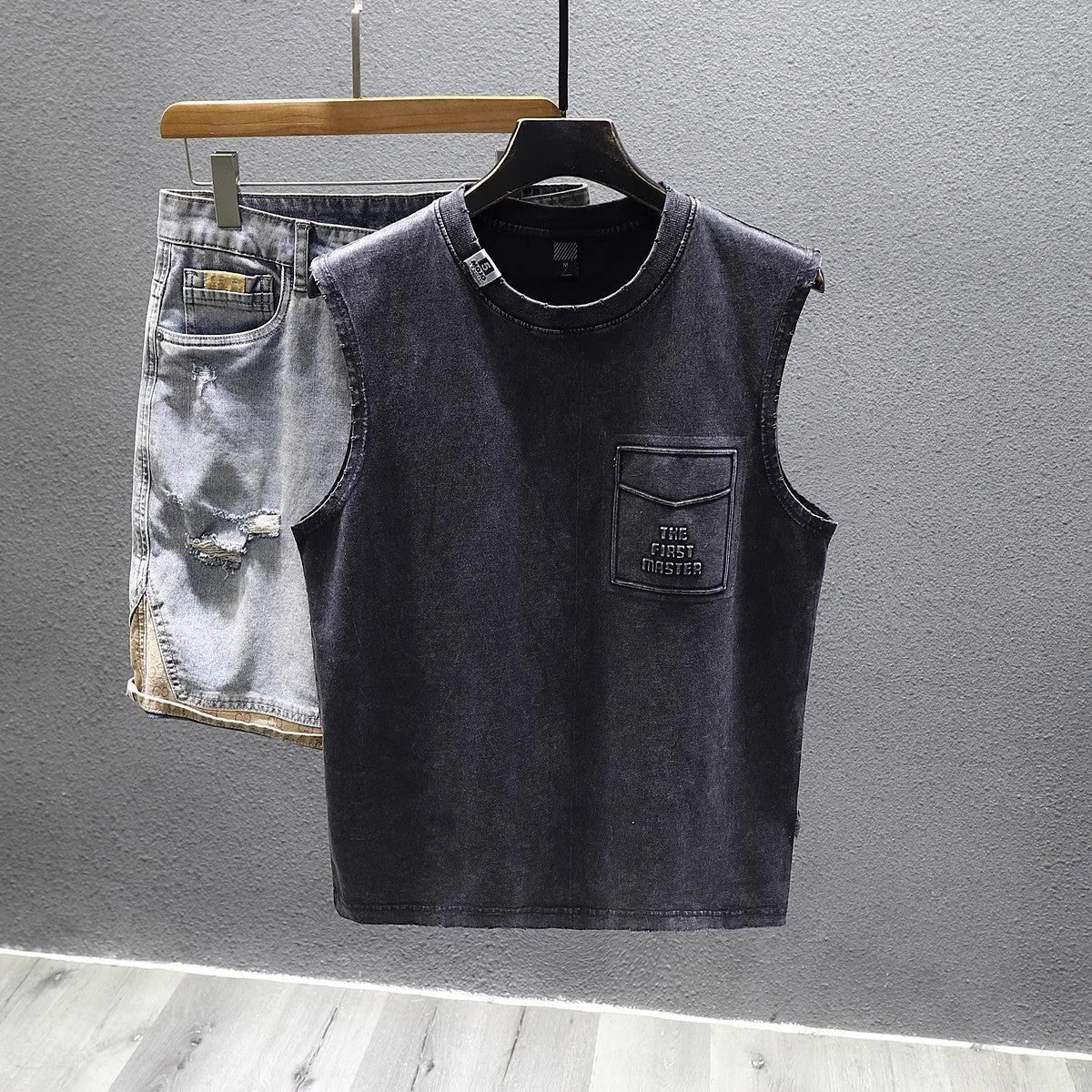 A man's solid black cotton sleeveless t-shirt with a loose fit and straight hem, laid flat.