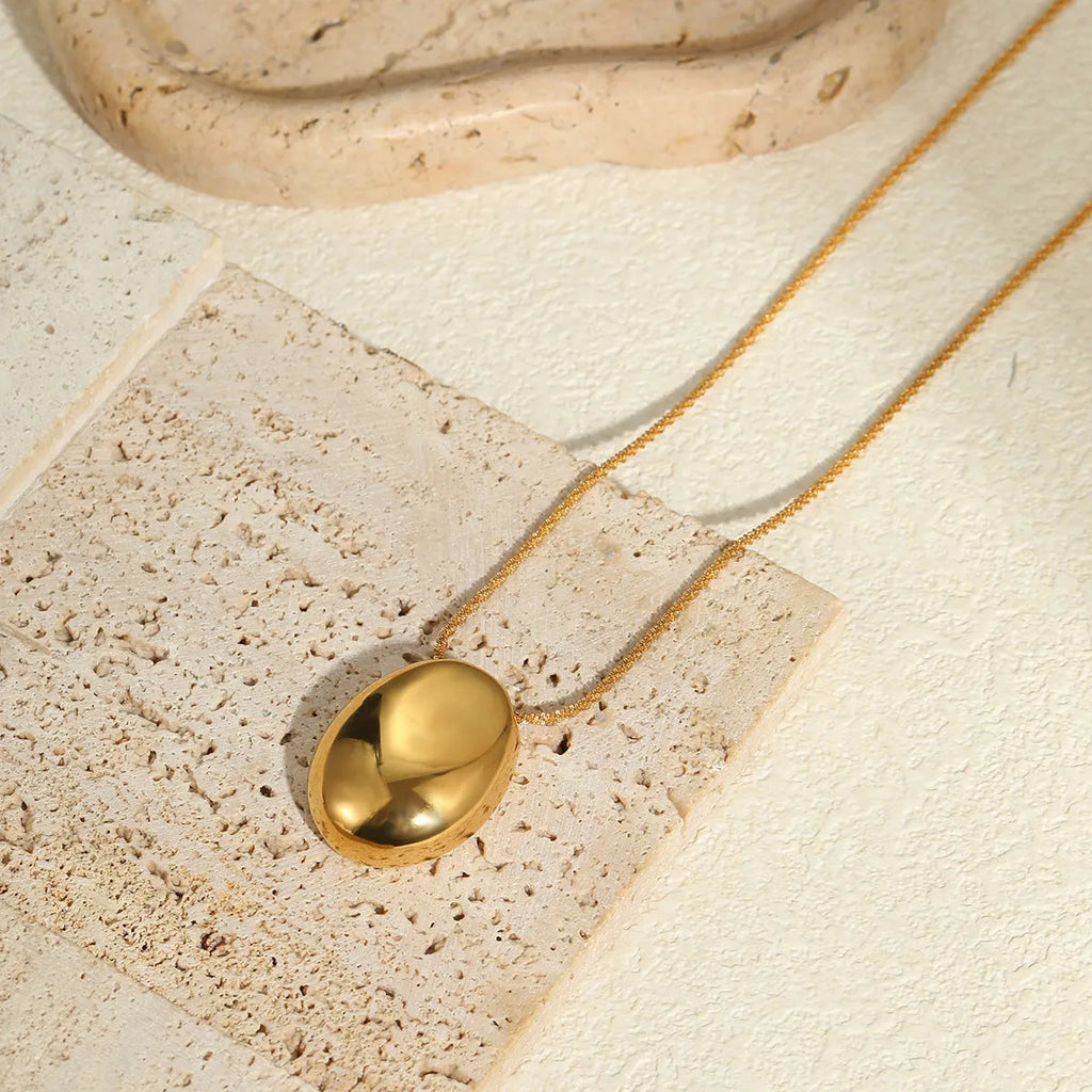Gold geometric pendant necklace with adjustable chain on white background