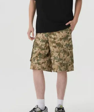 Man modelling loose-fit camouflage shorts in a retro workwear style for summer.