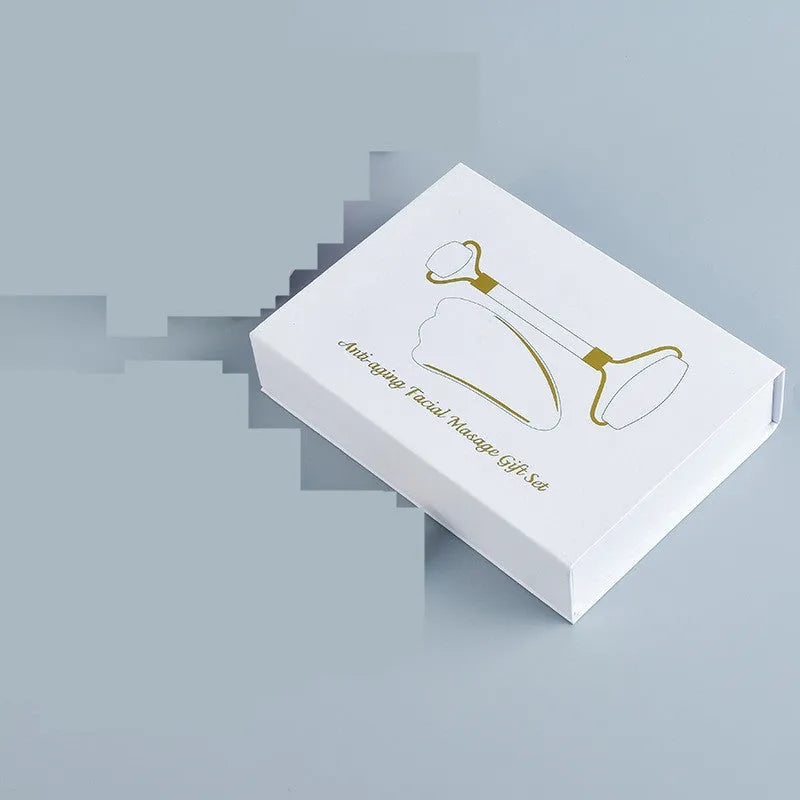 Natural white jade double-headed facial roller and matching scraping board set on a flat surface.