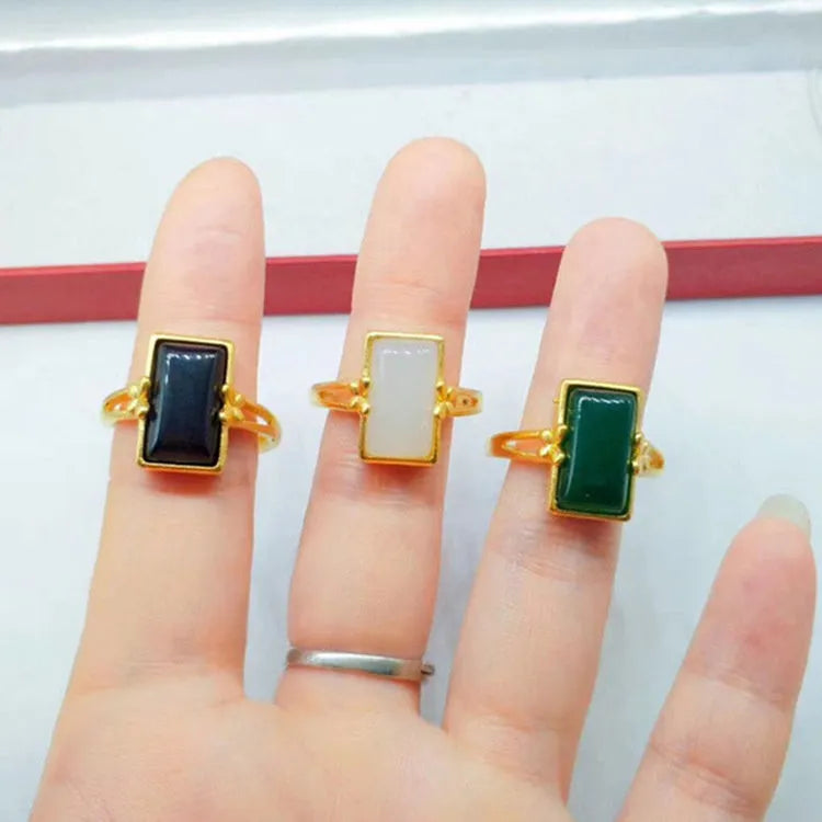 Adjustable brass gold-plated ring with a long black gemstone inlay on a finger.