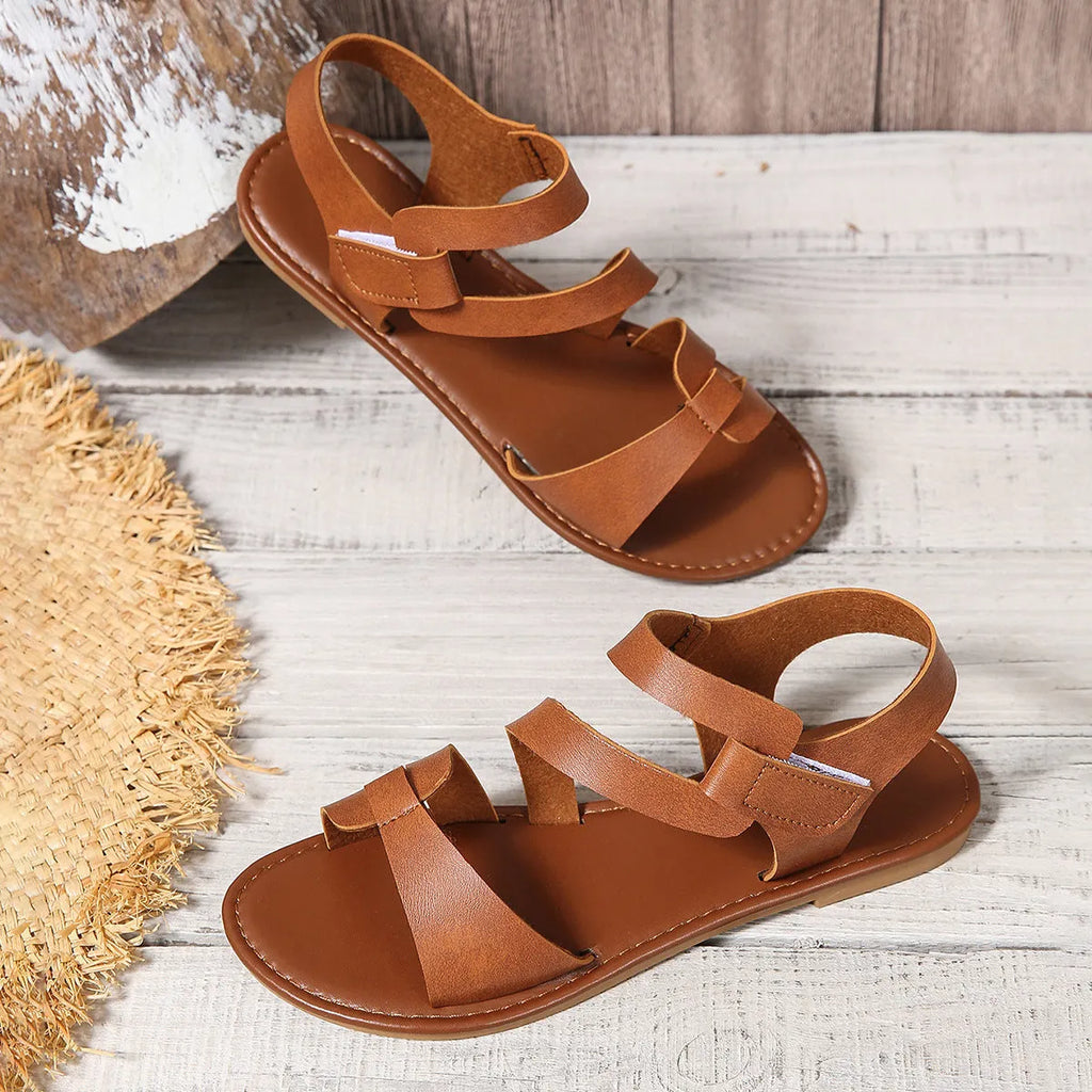 Women's flat sandals with Velcro strap, round toe, and rubber sole shown in black colour.