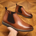 Men's black formal pointed-toe leather boots with a square rubber heel on a plain background