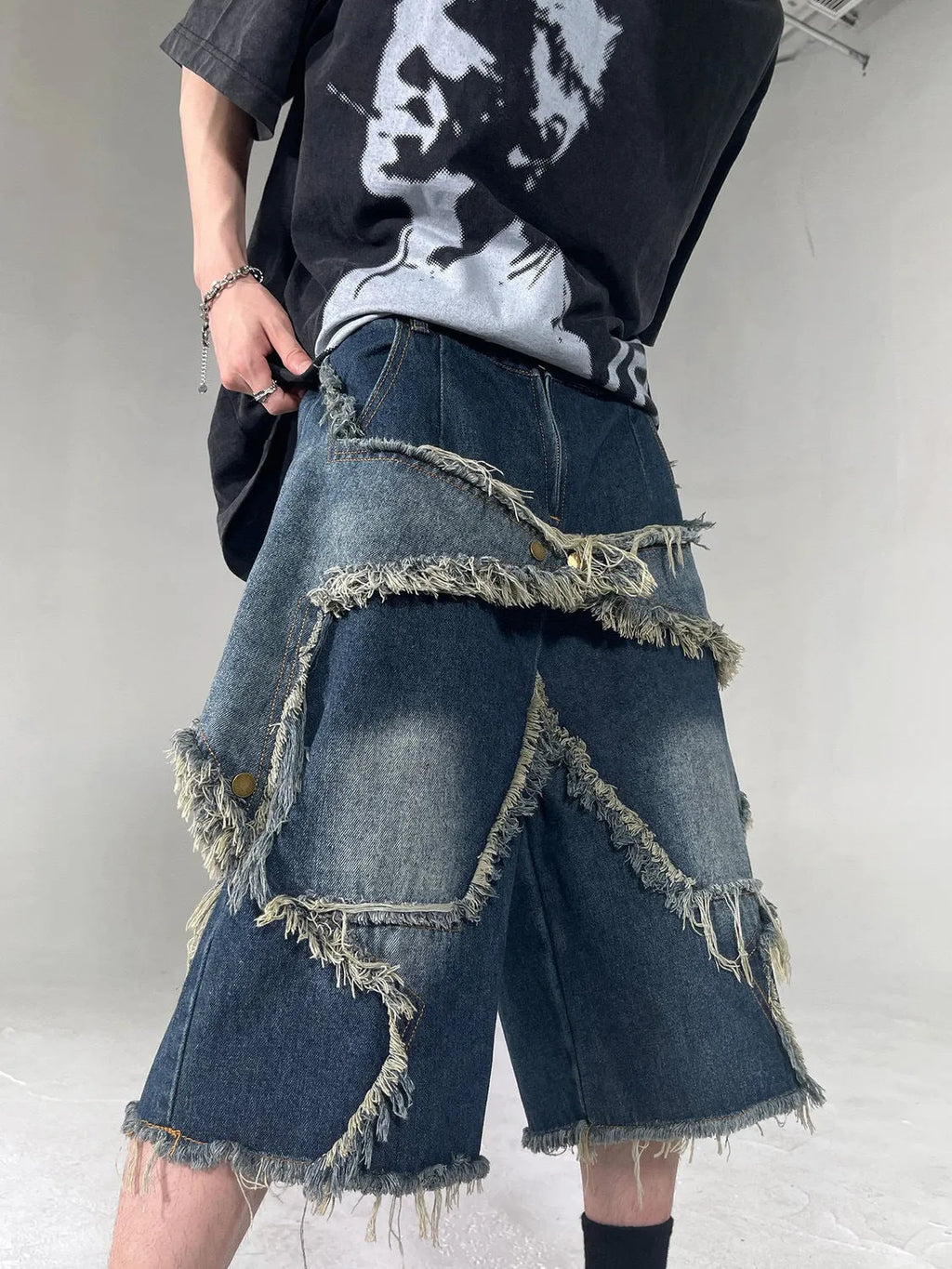 Blue denim shorts with frayed hem and star detail shown in loose fit style