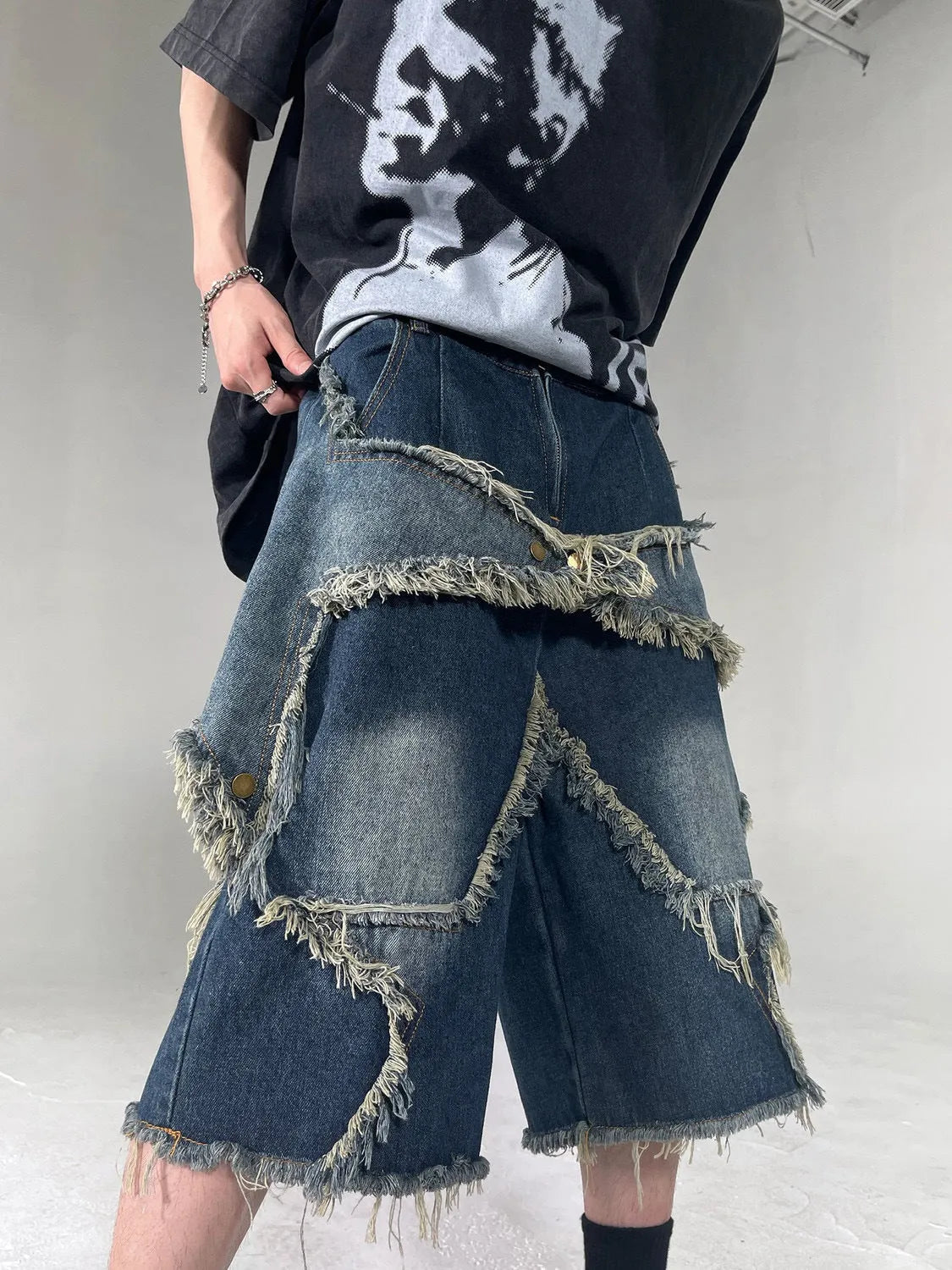 Blue denim shorts with frayed hem and star detail shown in loose fit style