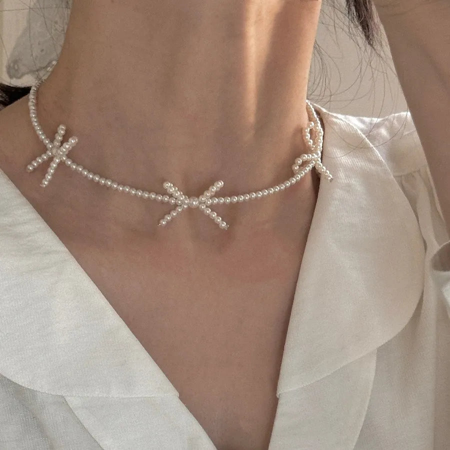 White imitation pearl necklace for women with an adjustable chain and a geometric sweet bow charm.