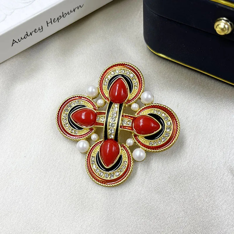 Vintage zinc alloy baroque cross brooch with crystal details on a dark fabric background.