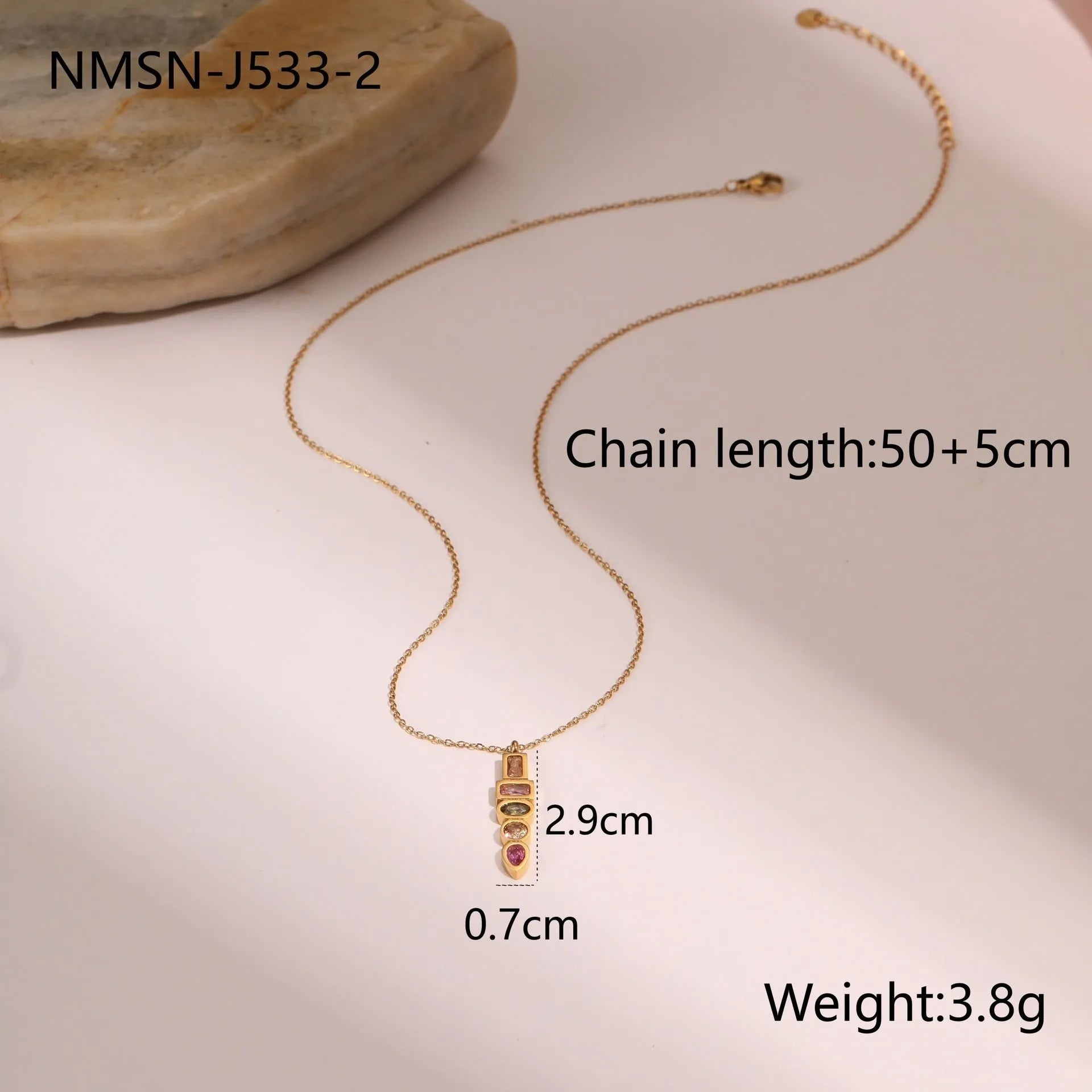Geometric gold plated zircon necklace, ring, and earrings set on a plain background