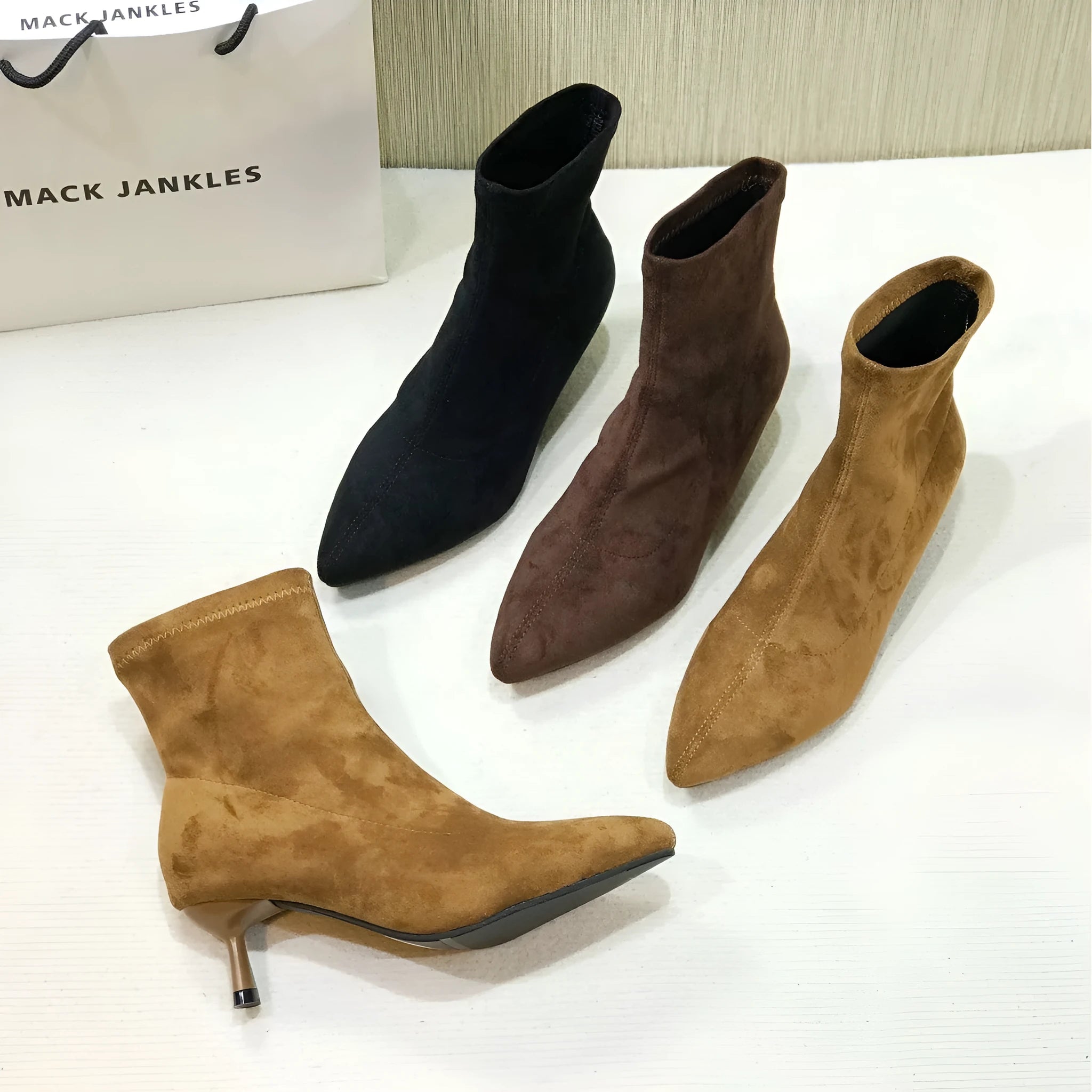 Black pointed toe women's ankle boots with a stiletto heel on a white background.