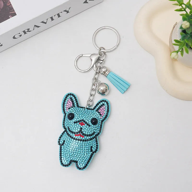 Close-up of a French dog style cartoon bear rhinestone keychain charm on a keyring.