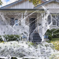 White cotton spider web Halloween decoration bundle with plastic spiders scattered on a dark background.