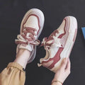 Pink and white low-top height-increasing sneakers with rubber soles on a plain background.