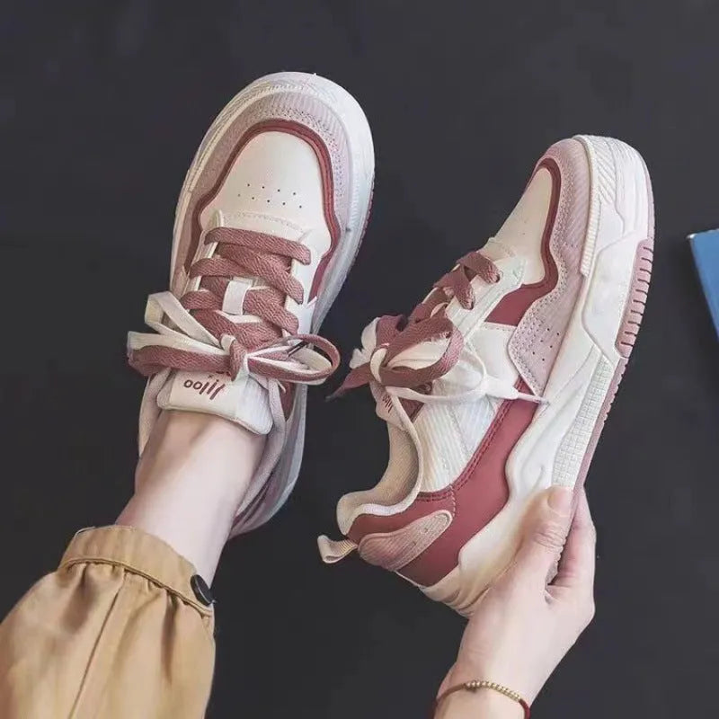Pink and white low-top height-increasing sneakers with rubber soles on a plain background.