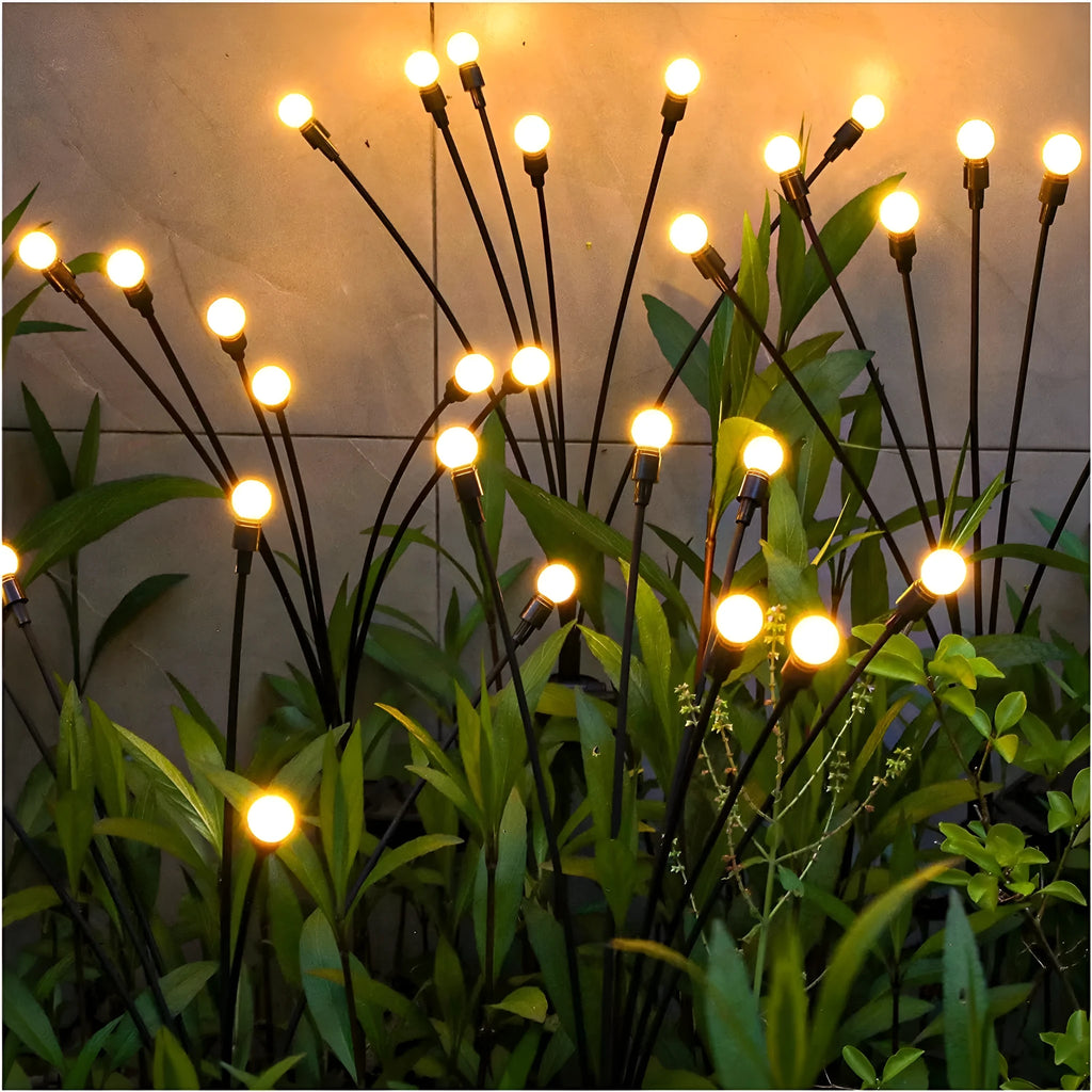 Solar-powered LED firefly garden spike light with stainless steel ground stake illuminated at dusk.