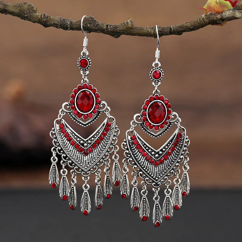 Close-up of long purple drop earrings with crystal fringe detail on an alloy setting.