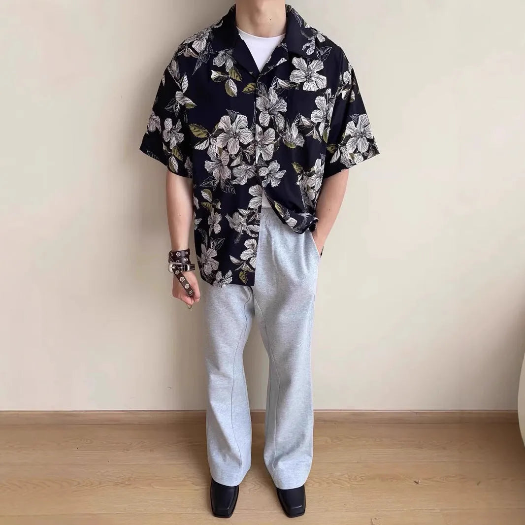 Man wearing a black ice silk shirt with floral print, Cuban collar, and short sleeves.