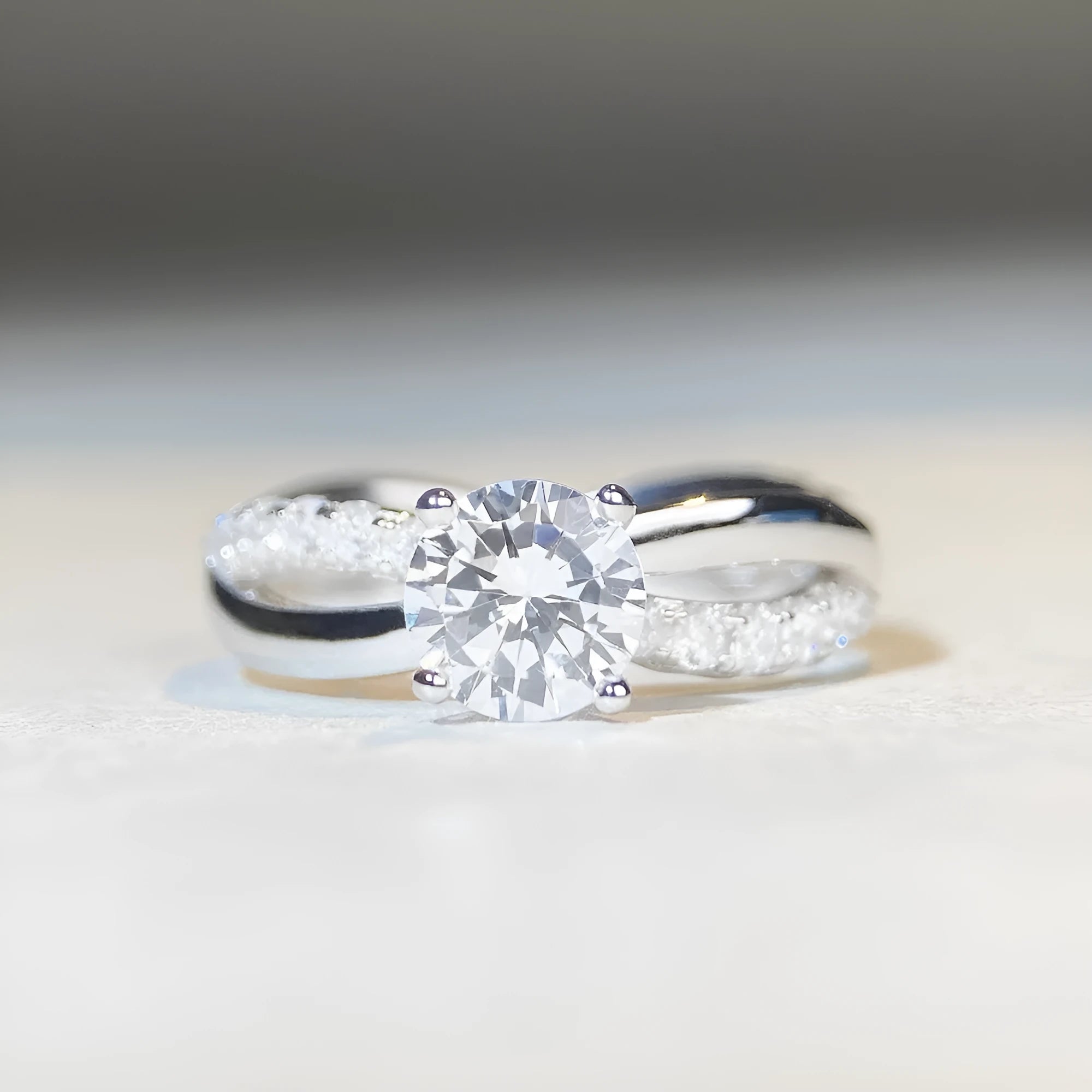 Women's silver ring with a 1 karat moissanite stone in a four-claw twisted arm setting, showing a geometric cross design.