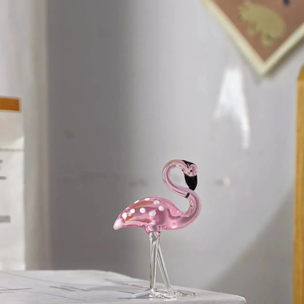 Clear crystal flamingo decorative sculpture with pink dots on a table.