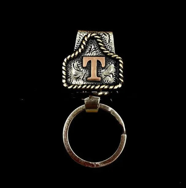 Handmade metal cow tag belt key holder keychain shown in one of twenty-six available colours, featuring a keyring and attached belt hook.