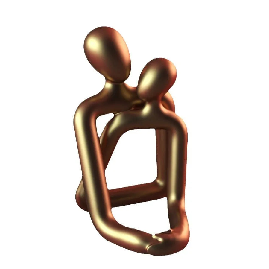 Modern couple resin statue in gold finish on a wooden desk.
