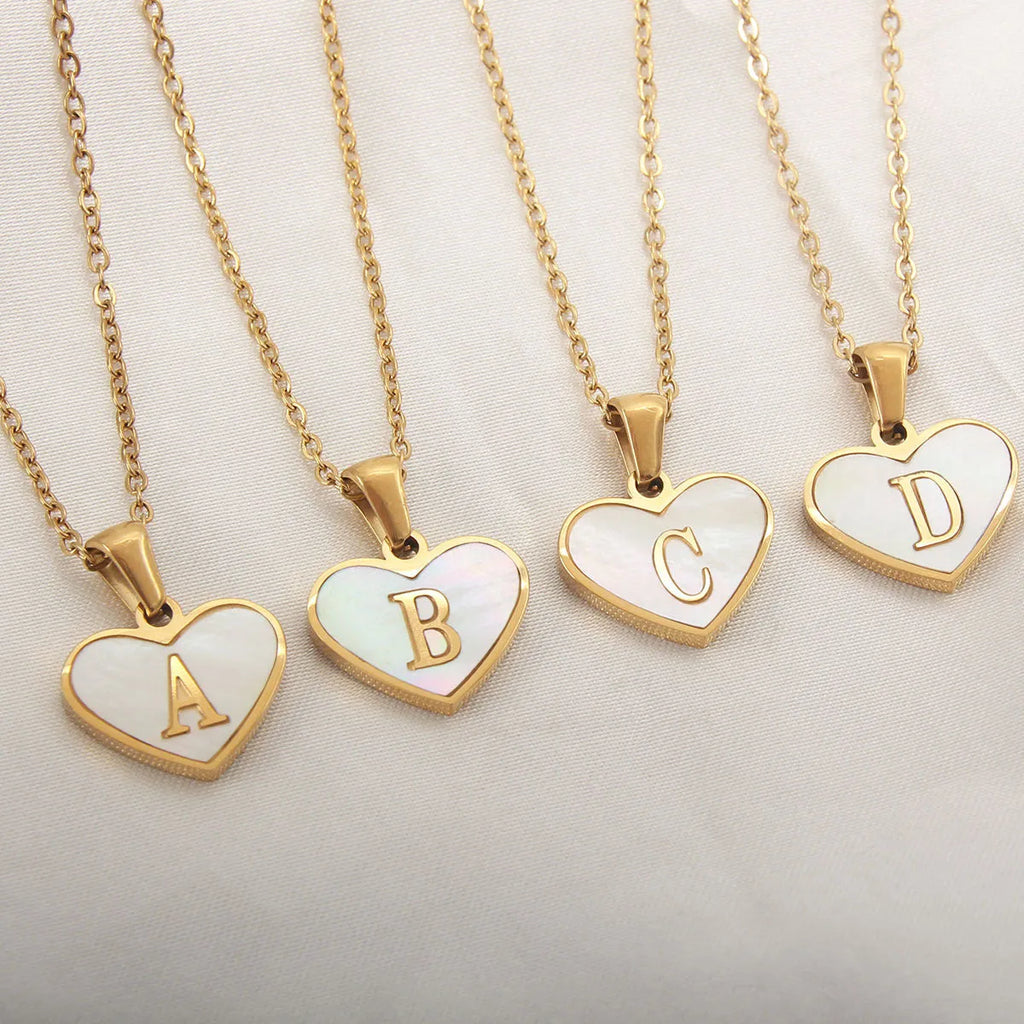 Gold chain necklace with white shell heart pendant featuring single letter customisation option
