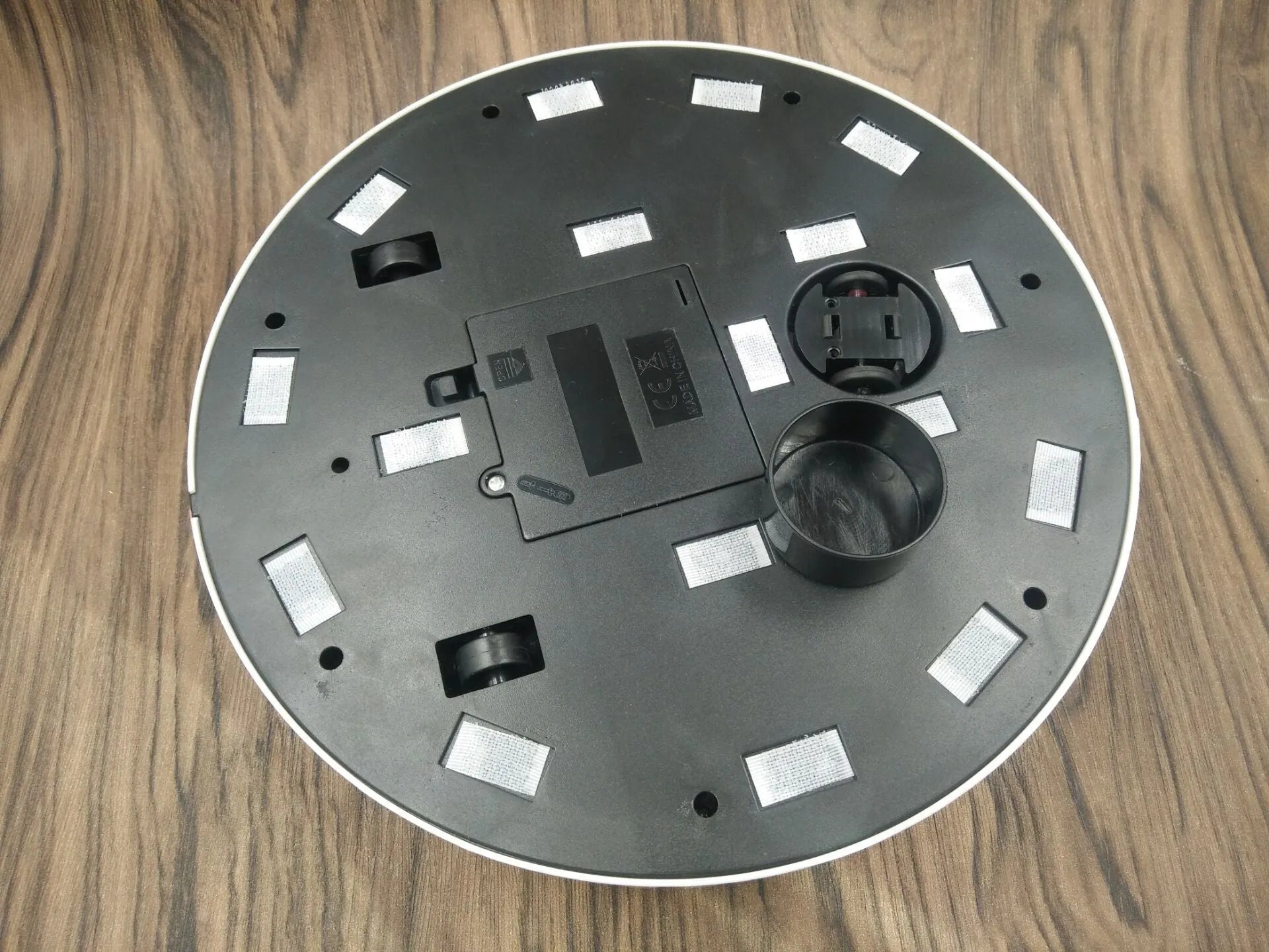Compact black and white robot vacuum cleaner on a wooden floor