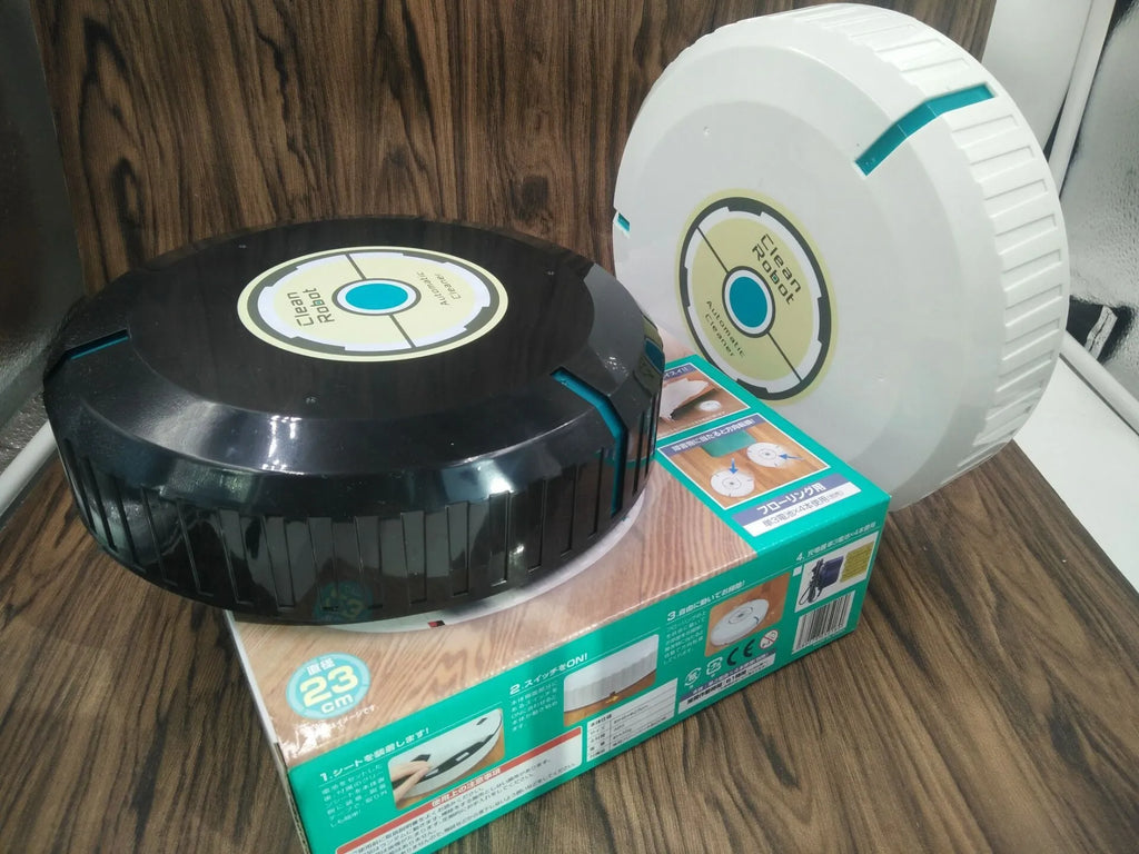 Compact black and white robot vacuum cleaner on a wooden floor