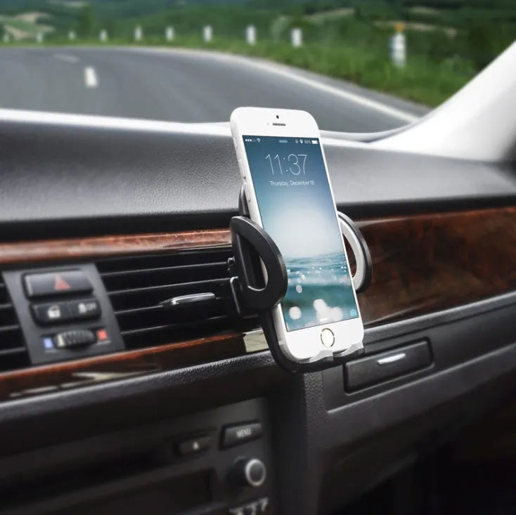 Black car air vent mobile phone holder attached to air conditioning outlet holding smartphone