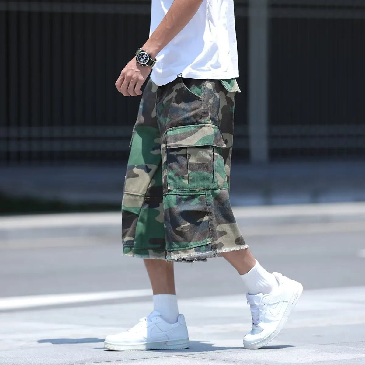 Man modelling loose-fit camouflage shorts in a retro workwear style for summer.