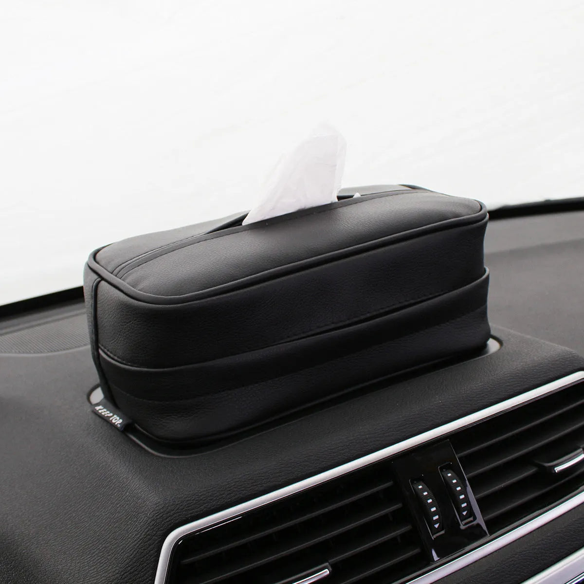 Black leather storage box with removable paper bag inside for car and home organisation.