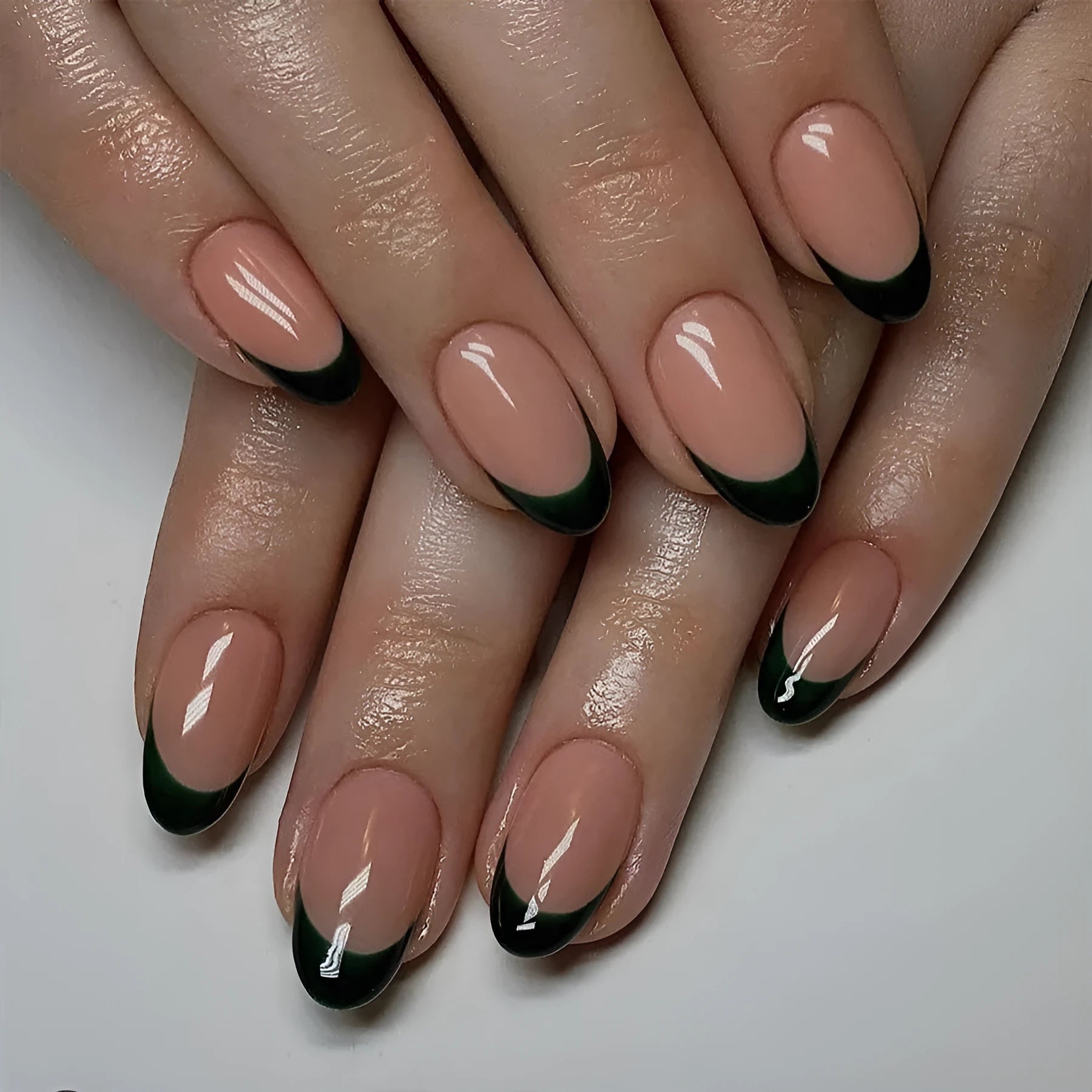 24 black French style false nails with short almond shapes laid out on a surface.