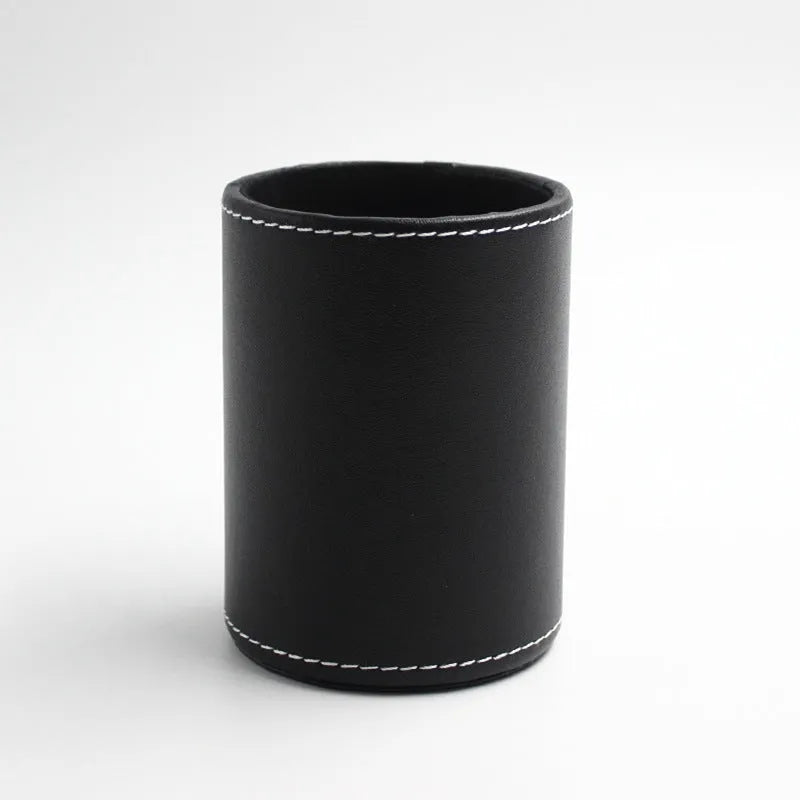 Black leather round pen holder with cylindrical shape on a desk