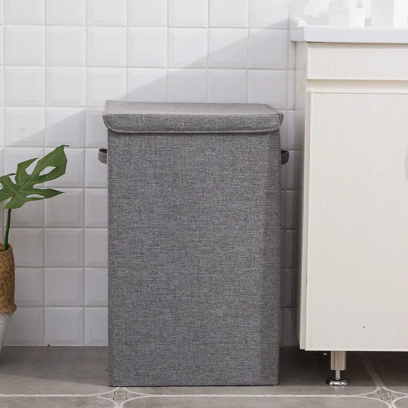 Grey foldable cotton linen storage basket shown next to a folded towel and a book.
