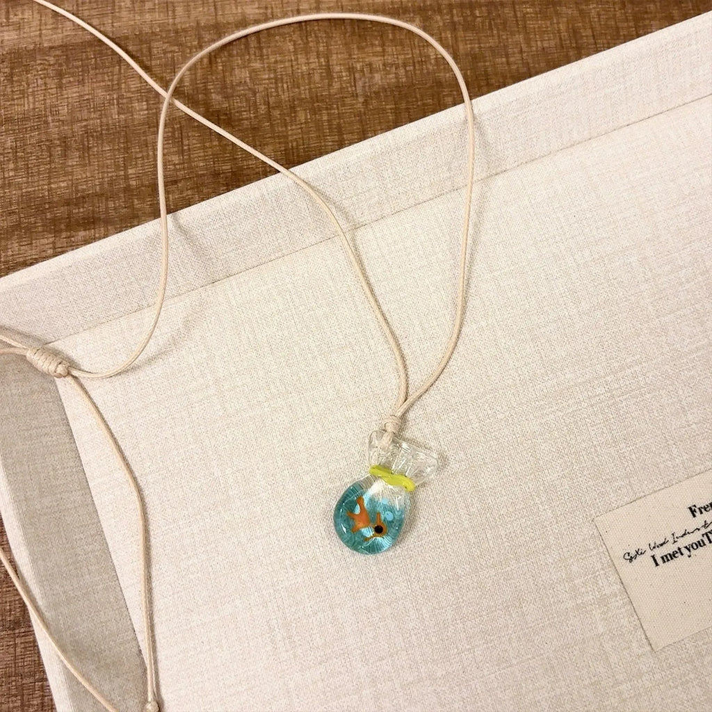 Women's necklace with coloured glaze joker pendant on a woven cotton and linen clavicle chain.