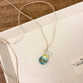 Women's necklace with coloured glaze joker pendant on a woven cotton and linen clavicle chain.