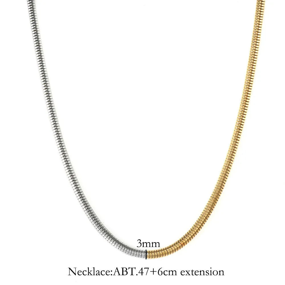 Close-up of a women's gold 3mm snake bone chain necklace with a geometric pendant.