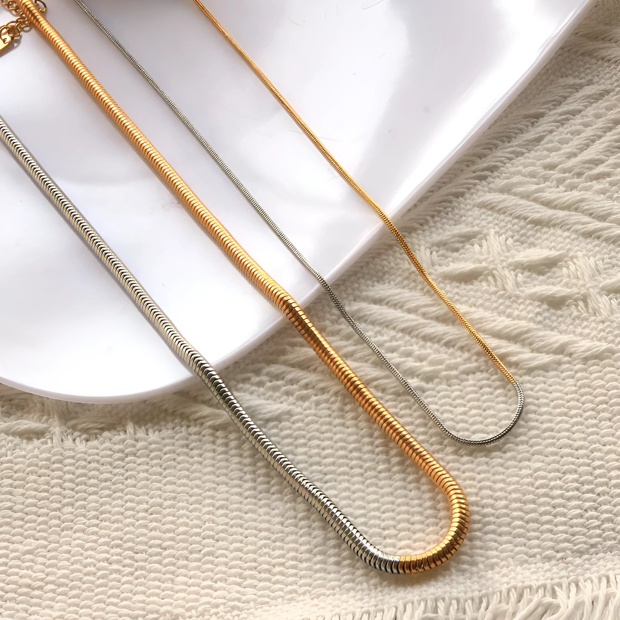 Close-up of a women's gold 3mm snake bone chain necklace with a geometric pendant.