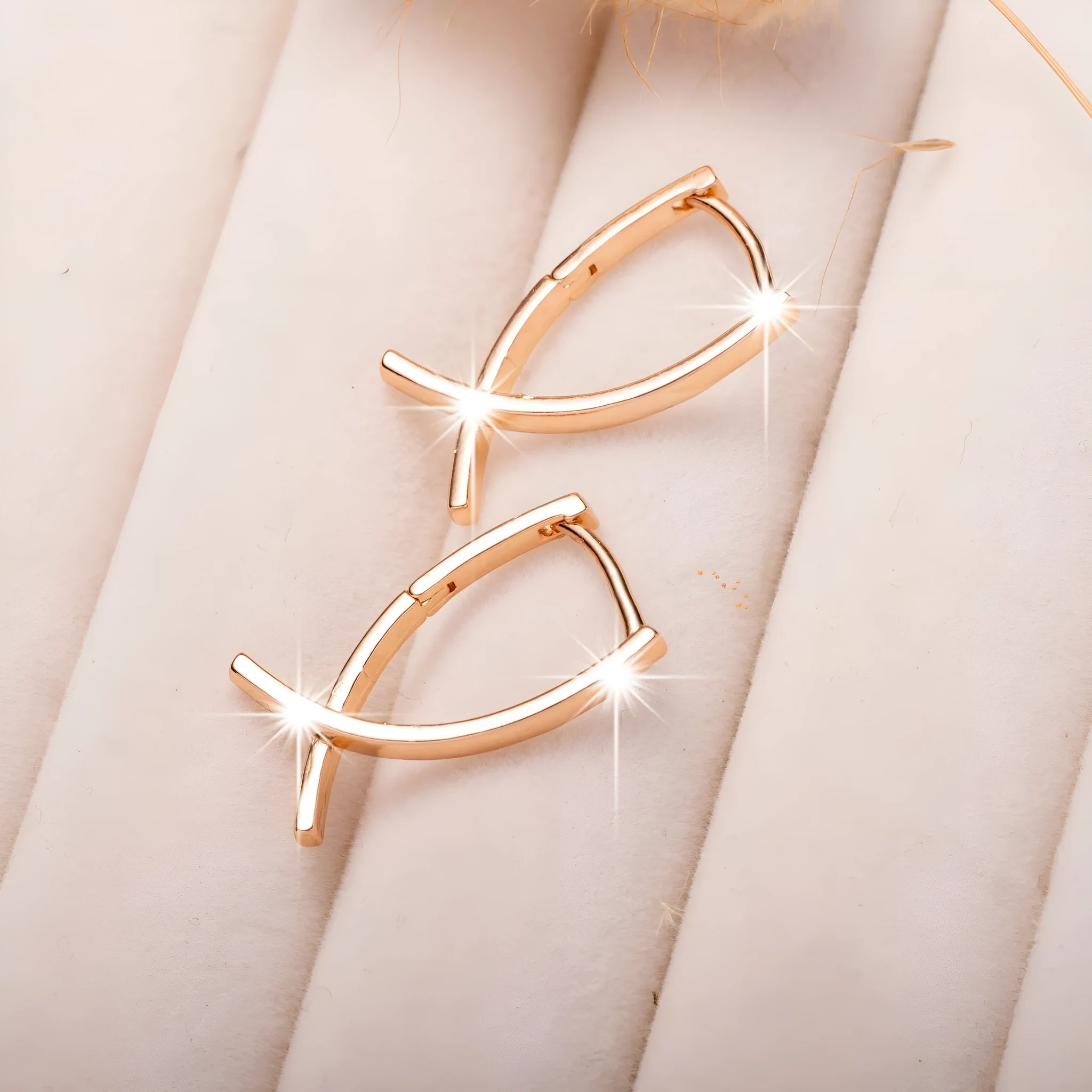 Rose gold cross shaped earrings with metallic finish and pendant design