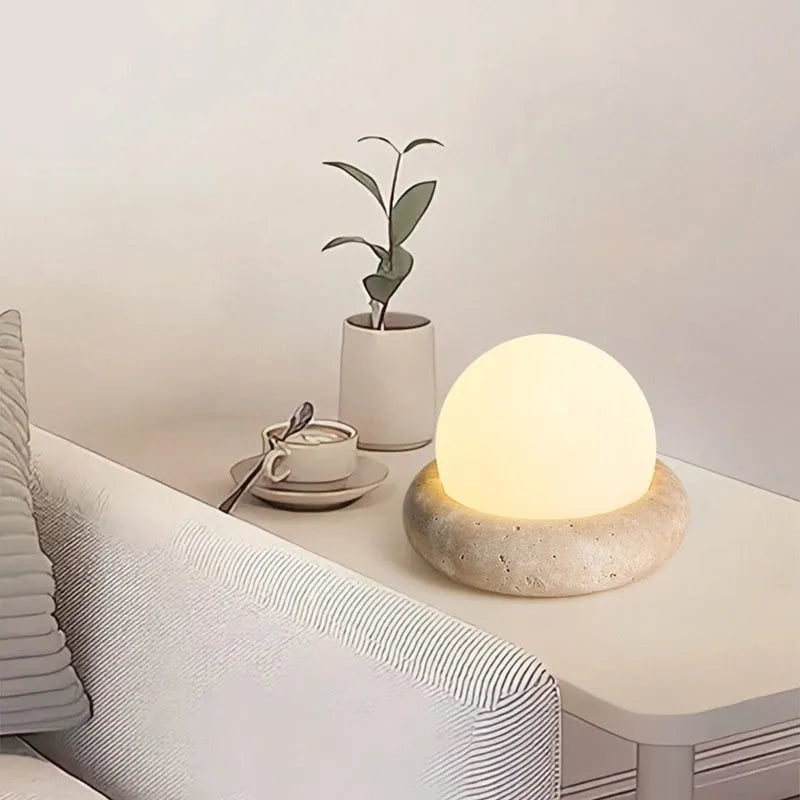 Cream-coloured round bedside night lamp with remote control on wooden table