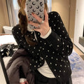 Women's grey dot knitted cardigan with long sleeves and crocheted flower detail.