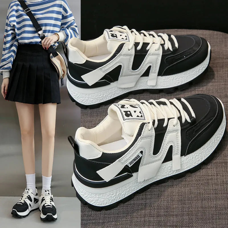 Unisex low-top sneaker in black with round toe, flat heel, and lace-up front on a rubber sole.