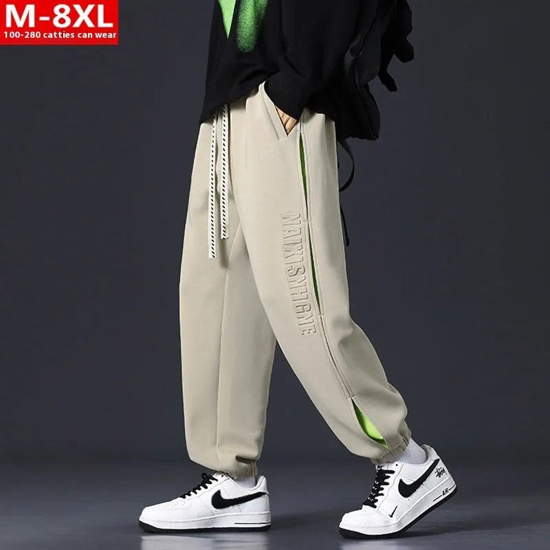 Man wearing grey green loose-fit cotton trousers with elastic ankle bands and visible stitch detailing.