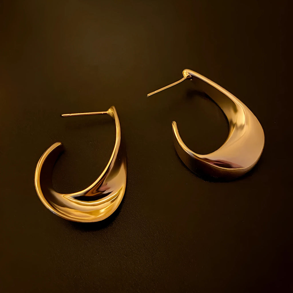 Metal twisted geometric earrings with electroplated gold or silver finish showing round design elements