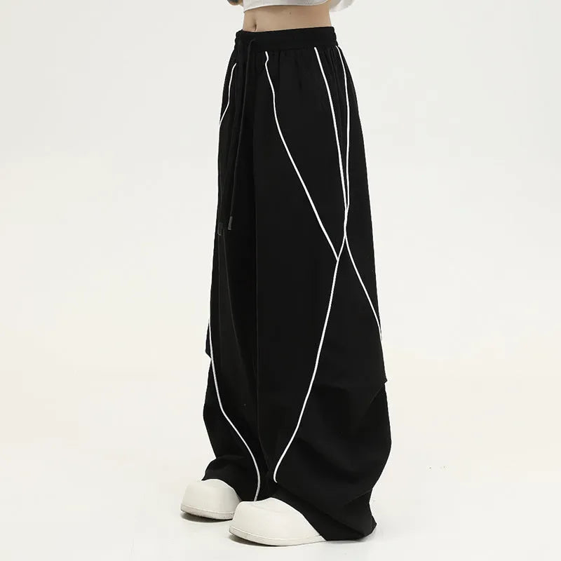Black and white striped pleated wide-leg hip hop sports pants on a mannequin, showing loose fit and mid waist.