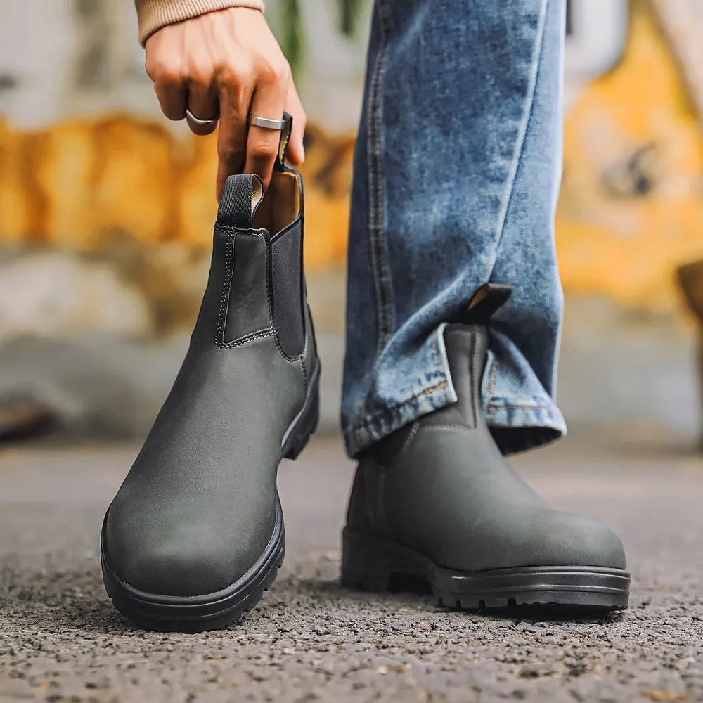 Vintage brown frosted finish Chelsea boots with car suture detailing on a wooden floor.
