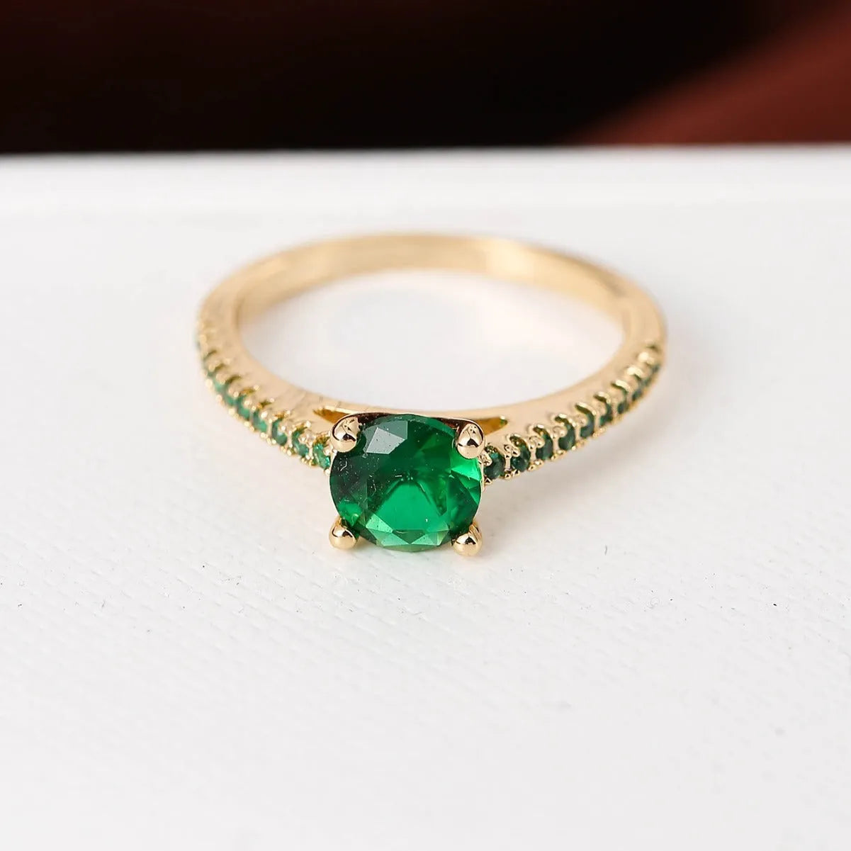 A geometric hexagonal zircon ring in copper, shown in a gold rose red electroplated finish on a size 7 finger.