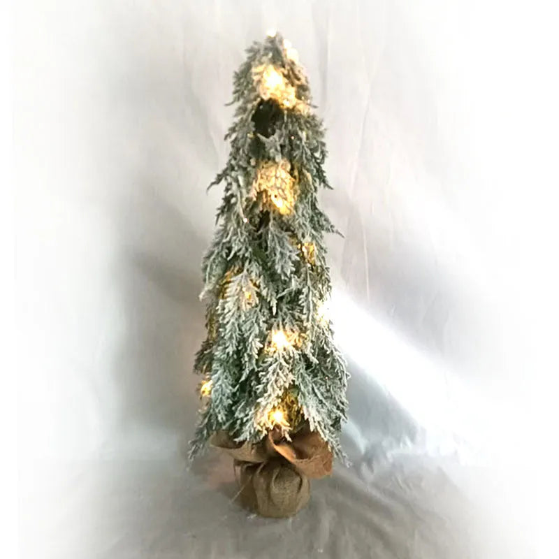Small 24-inch white artificial Christmas tree with built-in LED lights and simulated snow sprayer on a desktop.