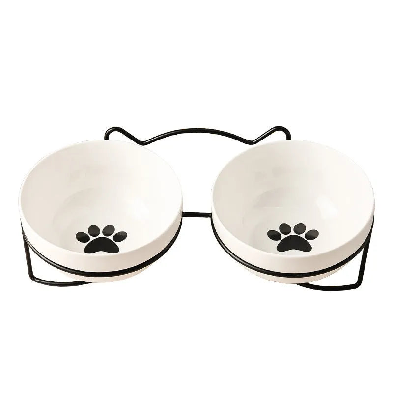 White ceramic cat food bowl with cat paw print design on black iron frame stand