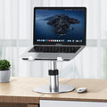 Silver adjustable aluminium laptop stand with rotating base on a desk.