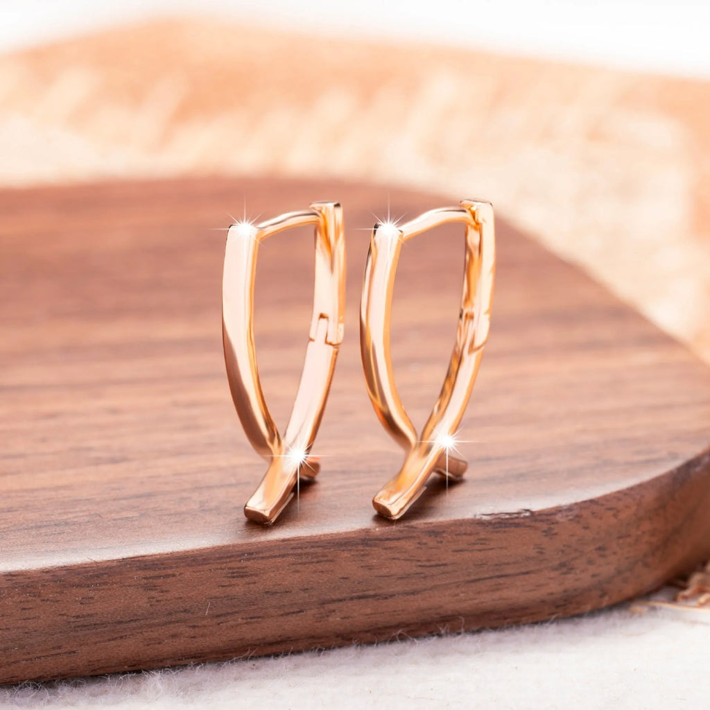 Rose gold cross shaped earrings with metallic finish and pendant design